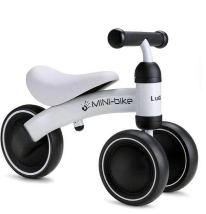 White mini balance bike for toddlers with black wheels and comfortable handle, perfect for developing balance and autonomy.